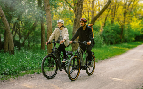 Zwei Fahrradfahrer mit Helm auf einem E-Bike.